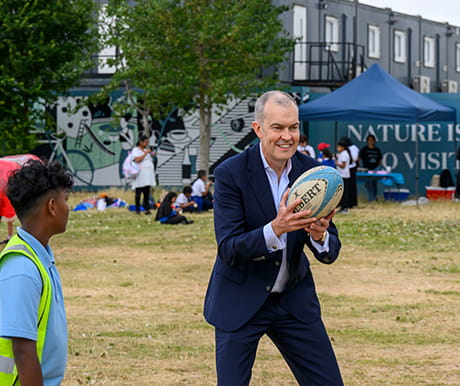 An image of a Trustee playing rugby with children at a charity event