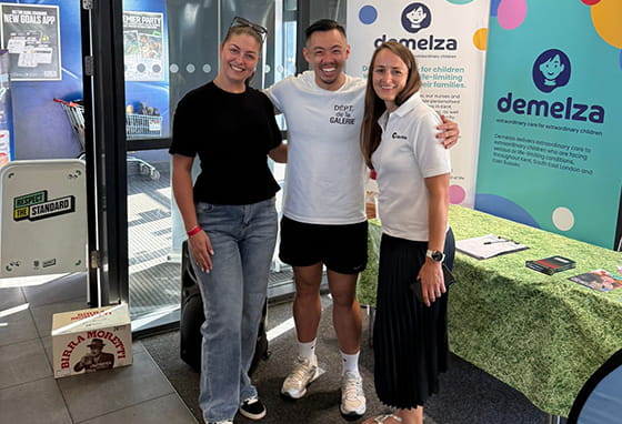 An image of people in front of signs for Demelza