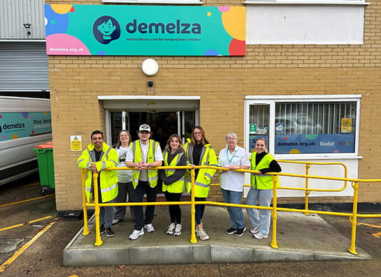 An image of people stood outside of the Demelza website