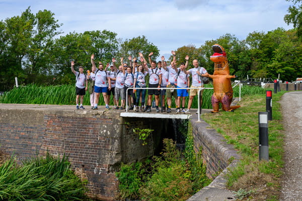 Berkeley employees and affiliates taking a group photo in Birmingham along a footbridge in an urban environment.
