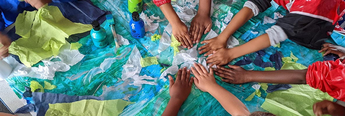 An image of children putting their hands together in a circle