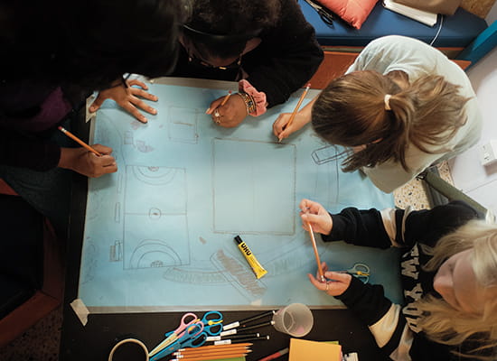 An aerial top down view image of a group of children drawing a picture together