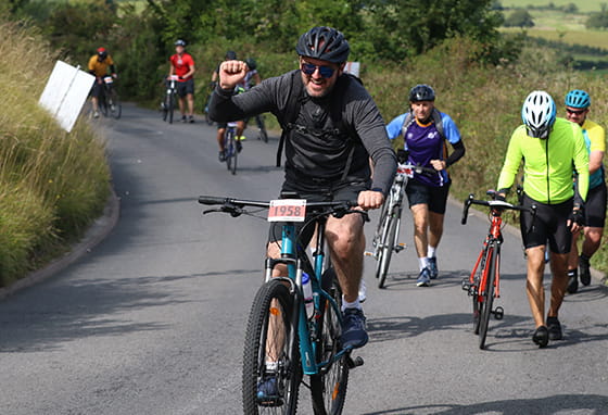 An image of people cycling up a hill
