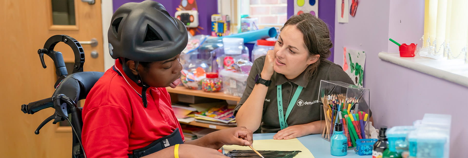 A care worker supporting a child drawing art